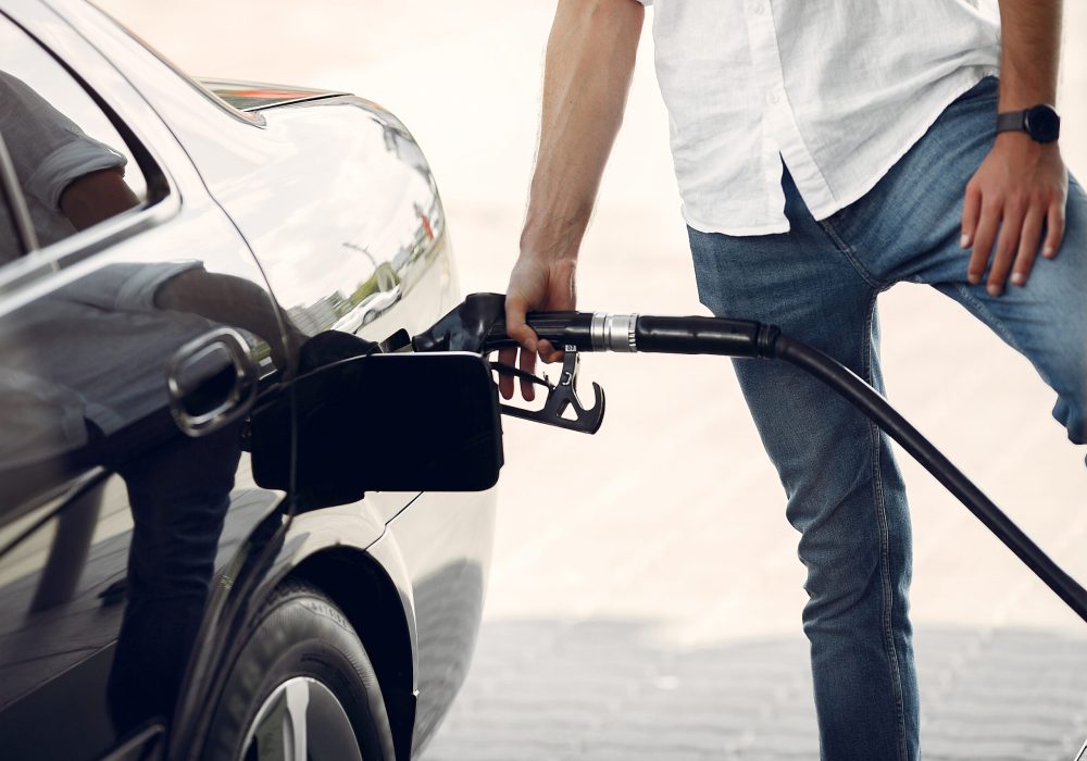 Man on a gas station. Guy refuelong a car. Male in a white shirt.